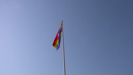 Rainbow-Pride-flag-gently-swaying-against-a-blue-sky-background