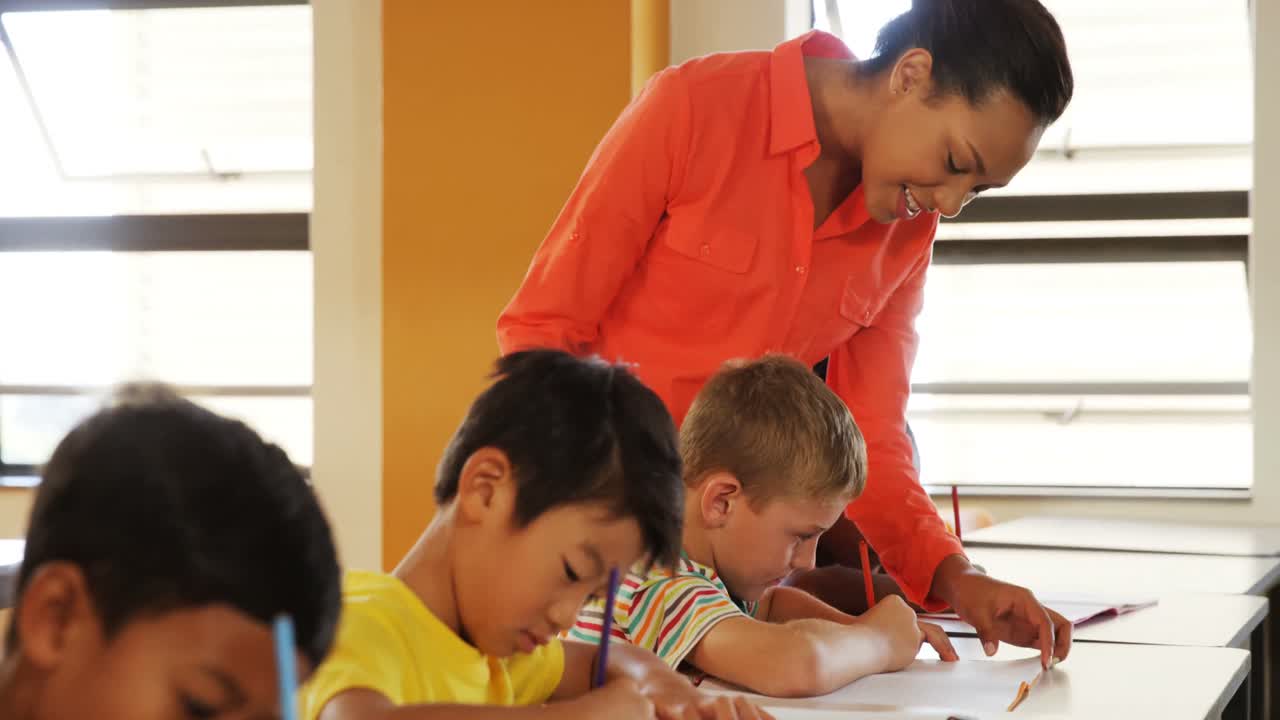maestro ayudando a los niños de la escuela con su trabajo de clase en el aula