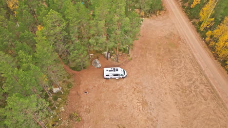 white campervan parked in autumn forest of sweden - aerial orbit