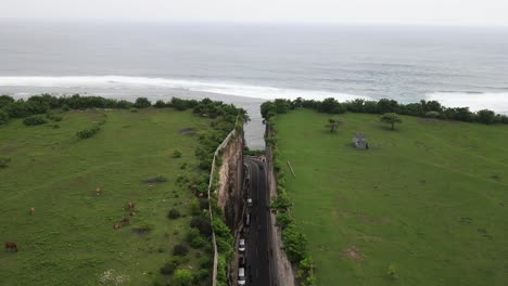 vista aérea, carretera de asfalto que penetra en los acantilados de tanah barak en la isla de bali para conectarse con la playa de pandawa