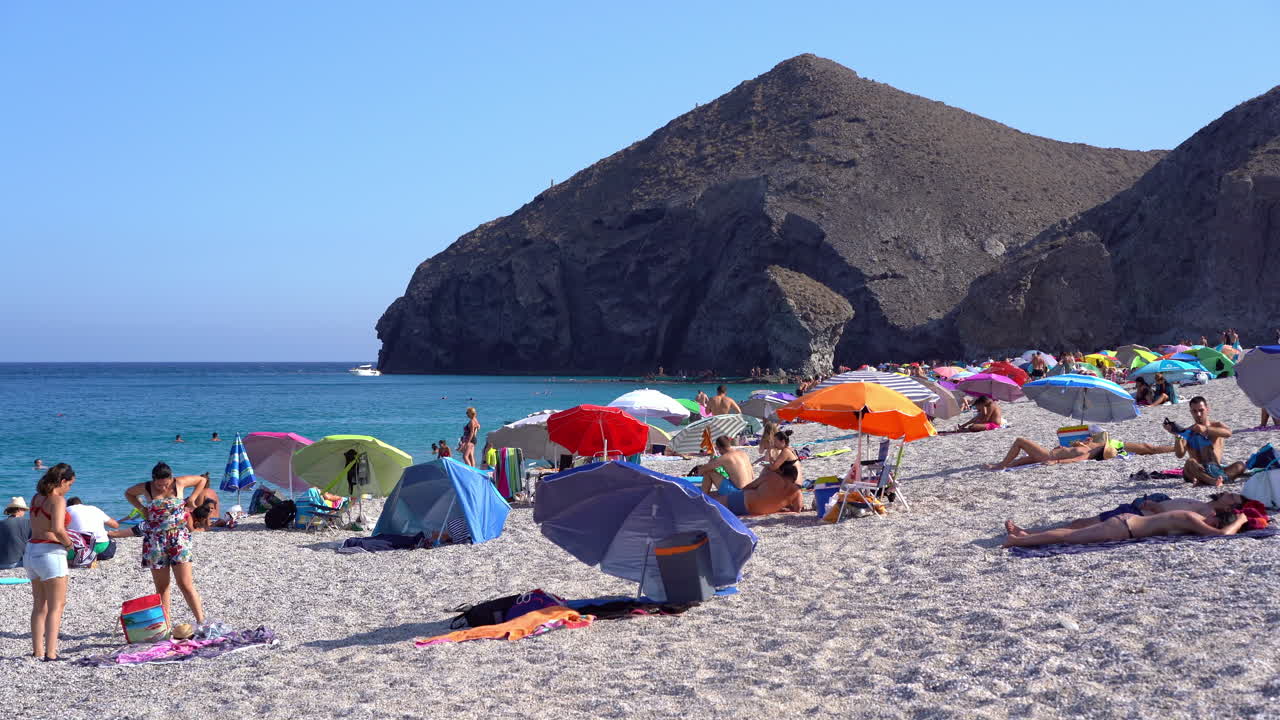 People dress on windy beach of Playa de los Muertos in Spain Static shot