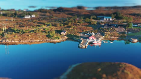 a scenic aerial view of a tranquil coastal village featuring a charming red boathouse and dock