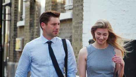 businessman and businesswoman walk to work along city street