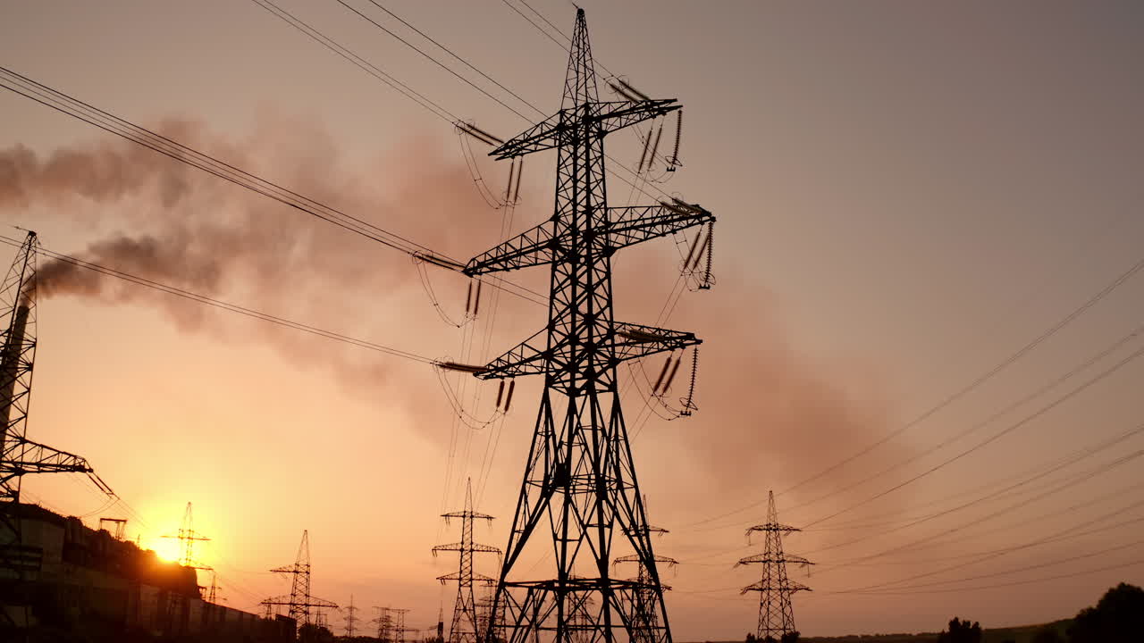 Electricity pylons at sunset. High-voltage electric tower on dirty sky background. Harmful smoke from industry filling the atmosphere. Air pollution.