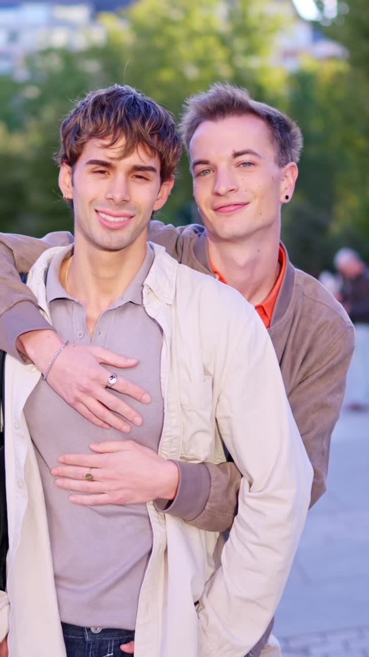 Giovane coppia gay felice che si abbraccia e sorride all'aperto
