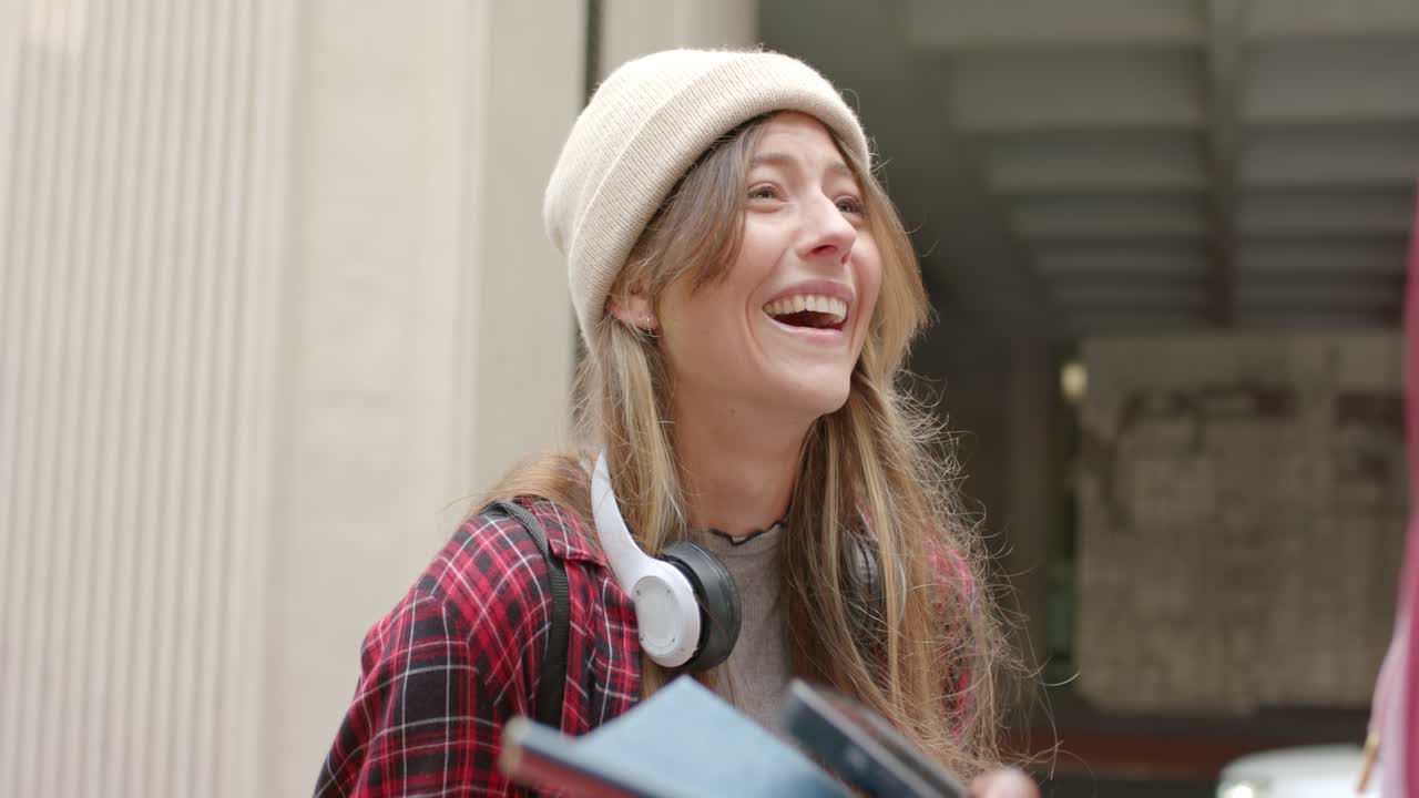 Donne di varie etnie sorridono e ridono dopo una domanda dell'intervistatore, su un viale, con berretti e cuffie.