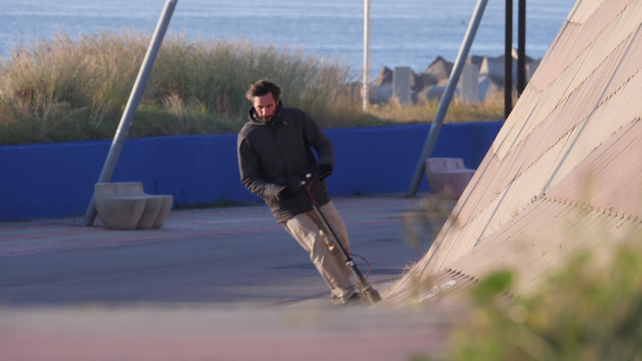 hombre monta scooter eléctrico por la rampa de la pared en el parque de barcelona con fondo oceánico