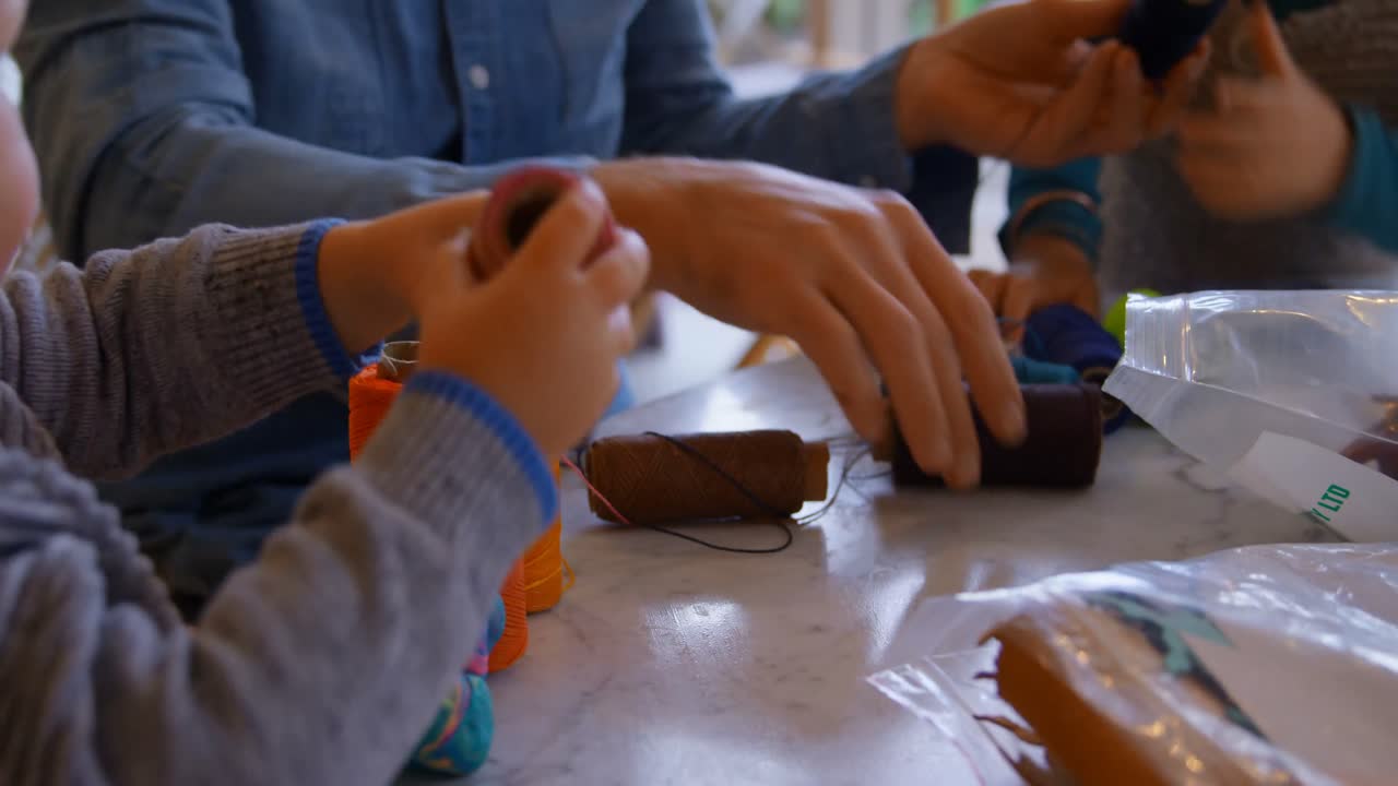 padre e hijos sosteniendo bobinas de hilo en la sala de estar en casa 4k