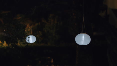 Linternas-Redondas-De-Papel-Blanco-En-El-Jardín-Nocturno.