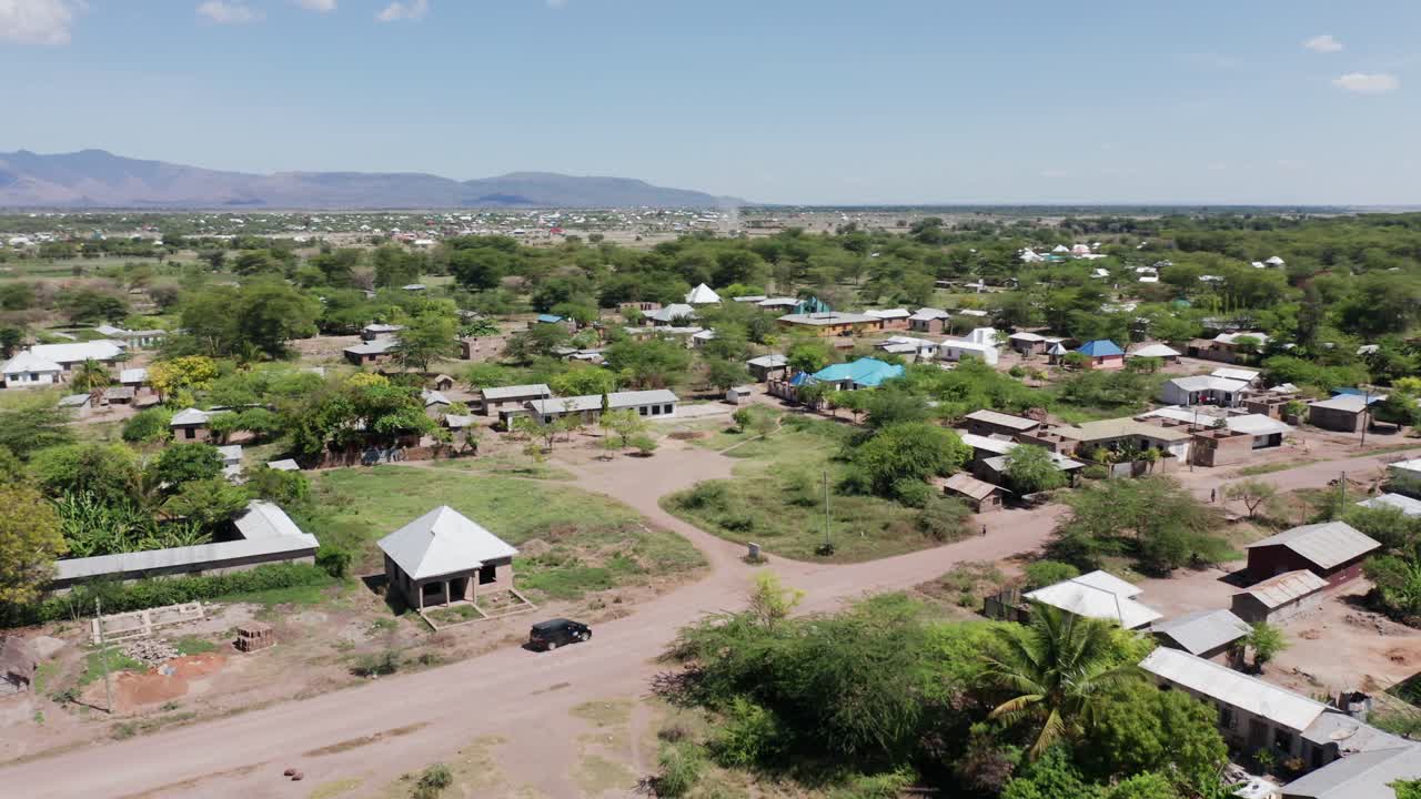 Aerial drone shot flying sideways over a little village next to Lake Manyara, Tanzania. Clear sky