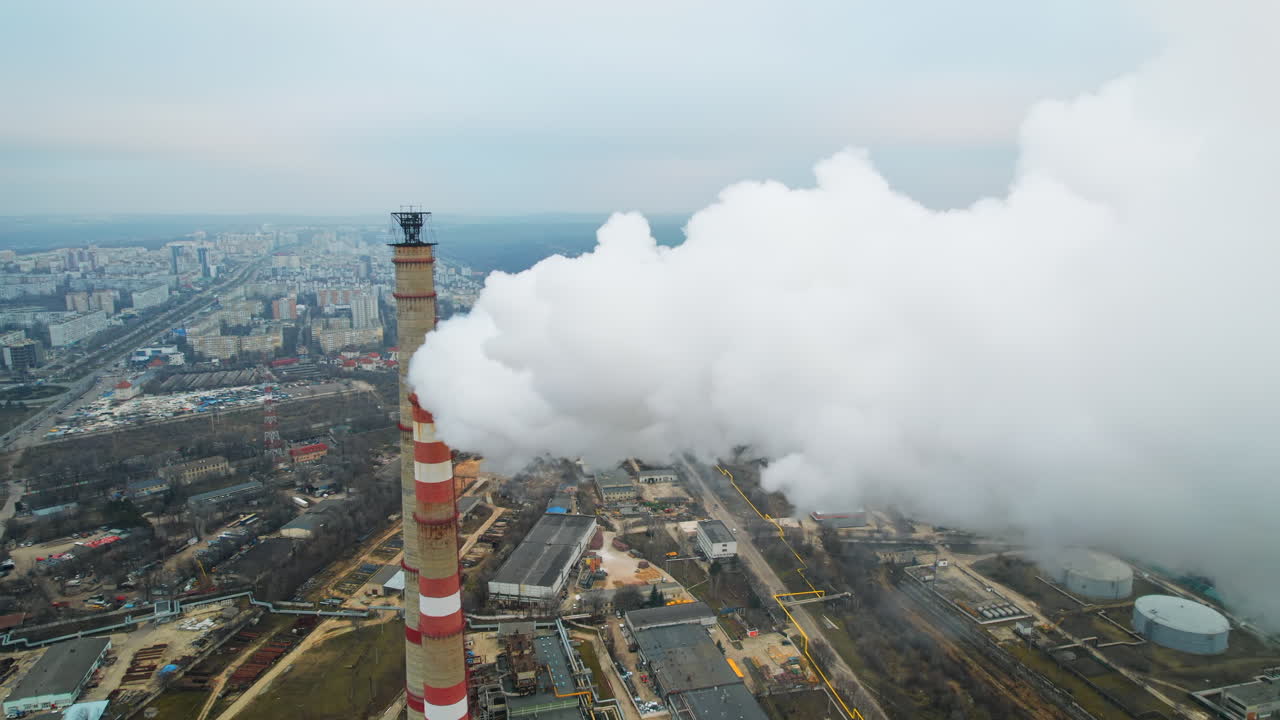 Aerial drone view of thermal power plant in Chisinau at cloudy weather, Moldova. View of pipes with felling steam, cityscape