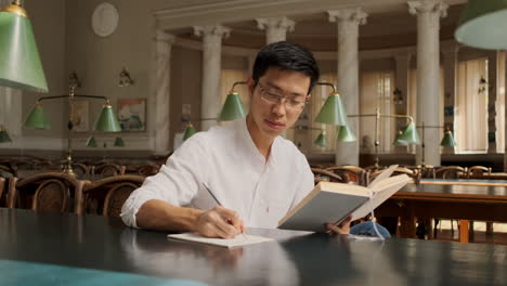 Young-asian-male-dreamly-taking-notes-in-library