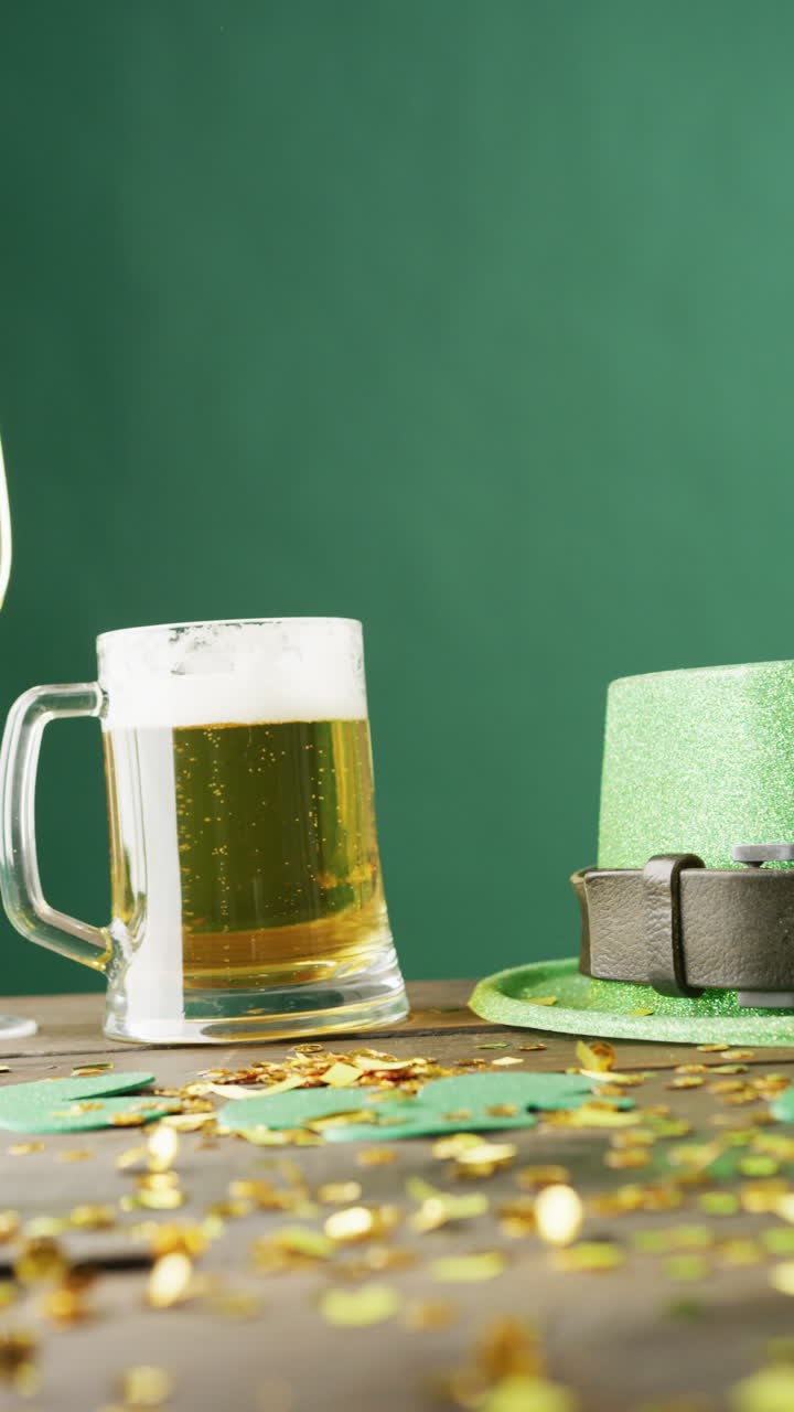 Vertical video of of st patrick's green hat, beer and champagne glasses on green background