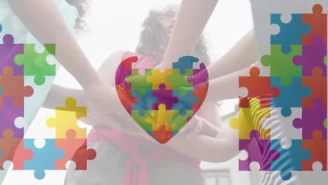 Animation-of-jigsaw-puzzle-forming-heart,-low-angle-view-of-diverse-children-putting-hands-together