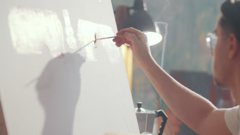 artist loading brush with paint and painting on canvas