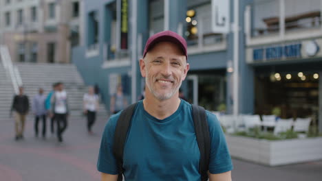 retrato de un turista caucásico maduro y atractivo con sombrero mirando a la cámara sonriendo el fondo de la ciudad