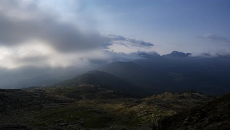 Clouds-moving-in-over-Lagorai-mountain-range-in-Italy-hugging-the-mountainside-and-tops-with-blue-skies-above