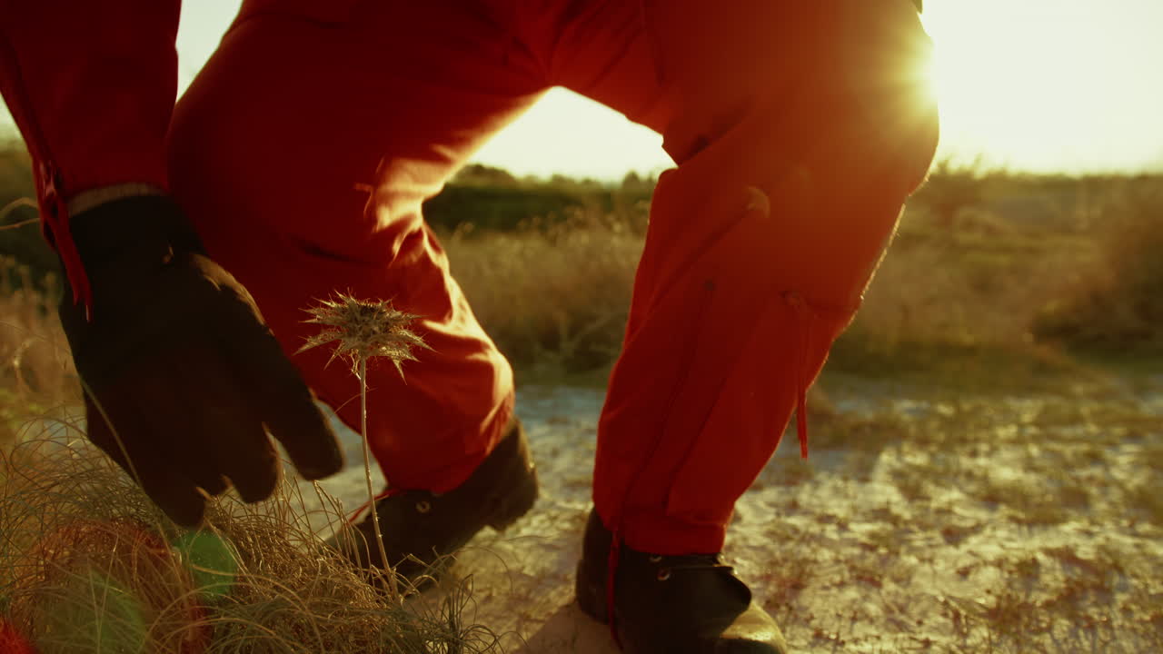 un astronauta en un traje naranja huele una flor venenosa en un planeta hostil