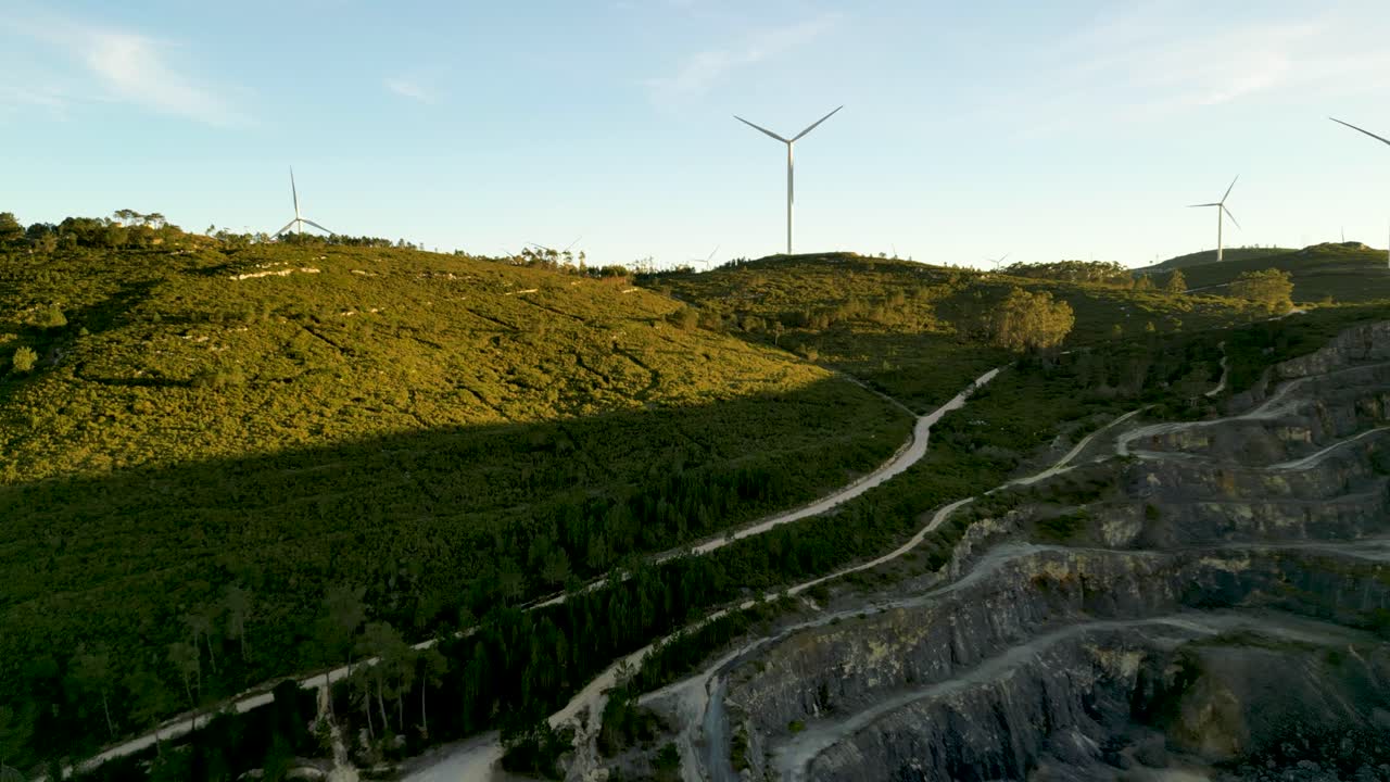 Vista aerea di turbine eoliche su colline verdi con cava sottostante