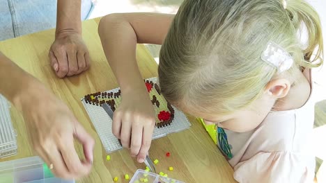 girl and adult crafting using pixel bead art