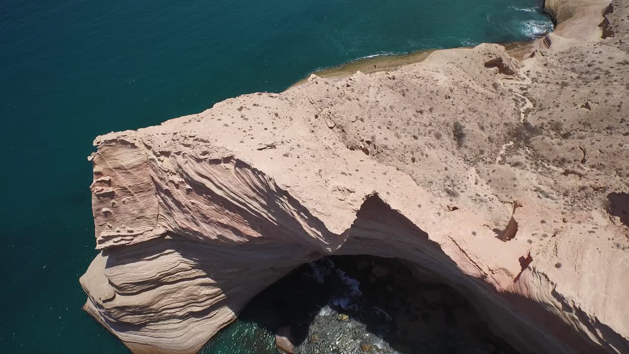 toma aérea de una impresionante formación rocosa y un buitre volando en punta colorada, mar de cortez