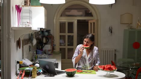 woman eating watermelon in the kitchen at night