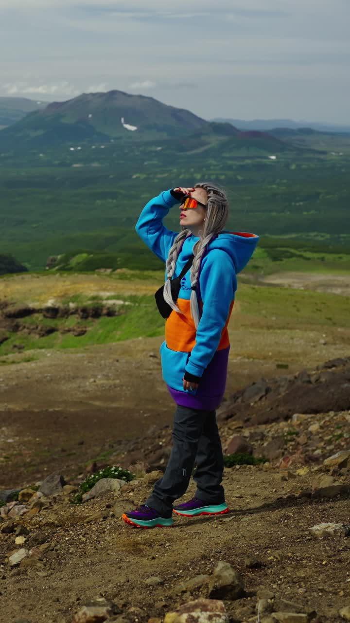 Woman Standing on Mountain Top Shielding Eyes from Sun