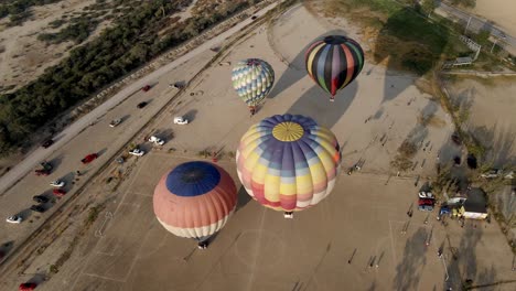 vista aérea de un colorido globo de aire caliente despegando durante el amanecer en un festival de globos en el campo