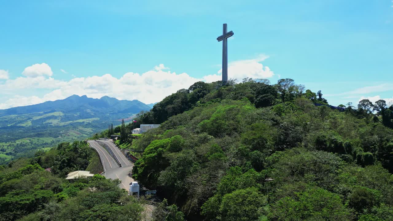 Slow rising aerial revealing the towering Mt. Samat National Shrine surrounded by lush forested hills, with sweeping views of valleys and mountains in Pilar, Bataan, Philippines