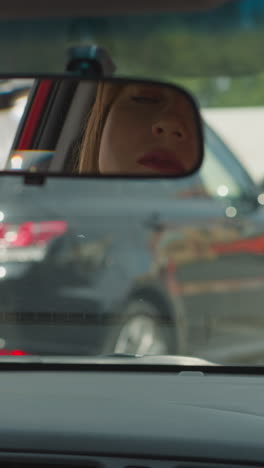 mujer con prisa mira en el espejo trasero del coche y las ventanas para comprobar la carretera. señora preocupada pone las manos en el volante esperando el semáforo verde de primer plano