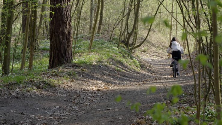 A girl is riding a bike on a forest path