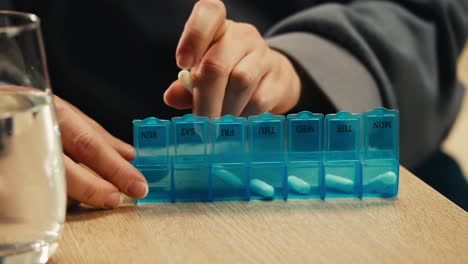 person taking daily medication from pill organizer