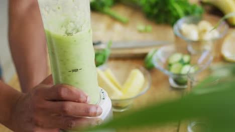 hombre afroamericano en forma cocinando, preparando un batido verde saludable