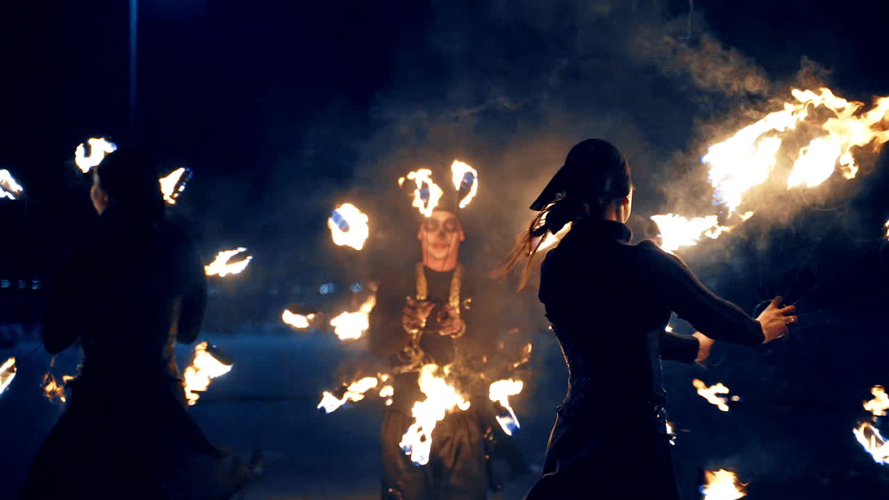 Spectacular fire show at night performed by the group of artists. Dancers move with burning props.