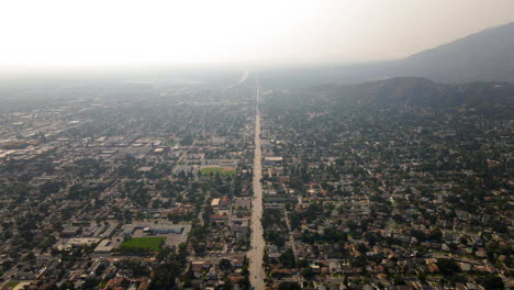 Aerial View of a Suburban City with a Long Road and Hazy Mountains