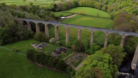 aerial view following narrow boat on trevor basin pontcysyllte aqueduct crossing in welsh valley countryside reveal orbit left