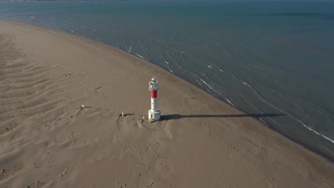 Aerial-view-of-lighthouse-on-shoreline-of-beach-in-Spain