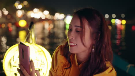 Woman-in-yellow-Ao-Dai-using-smartphone-at-night-in-Hoi-An