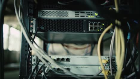 Wires and servers are interconnected in a data center. The environment is filled with blinking lights, showcasing operational systems and essential networking.