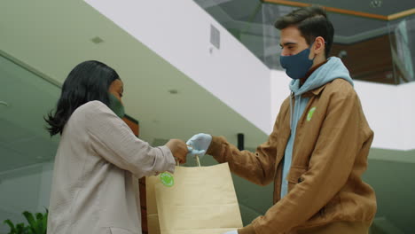 mujer de negocios recibiendo una bolsa de un repartidor con máscara