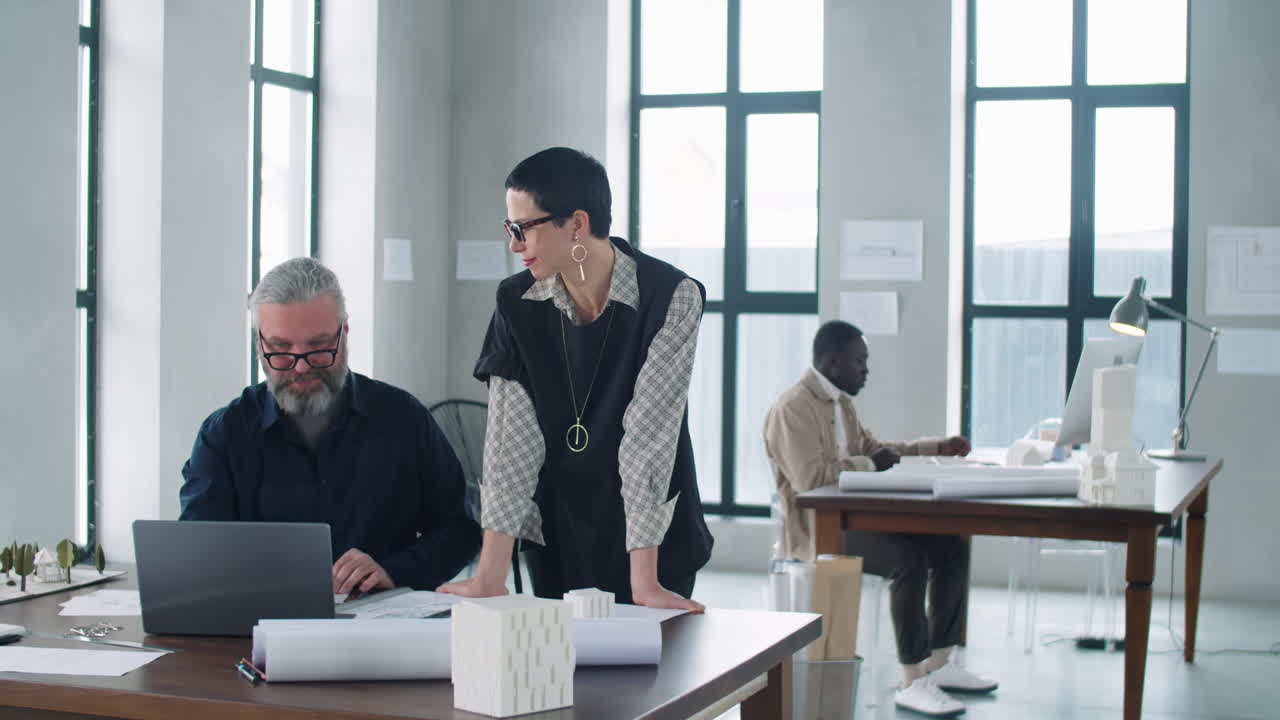 Architetta che discute un progetto sul laptop con un collega uomo senior