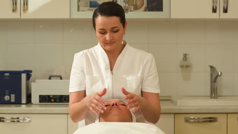 massage therapist making facial massage at beauty spa