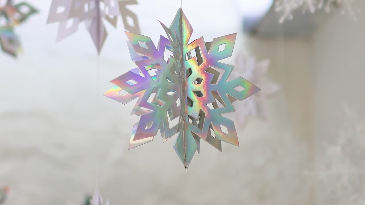 Close-up view of shimmering, holographic snowflakes gracefully swaying against a soft background.