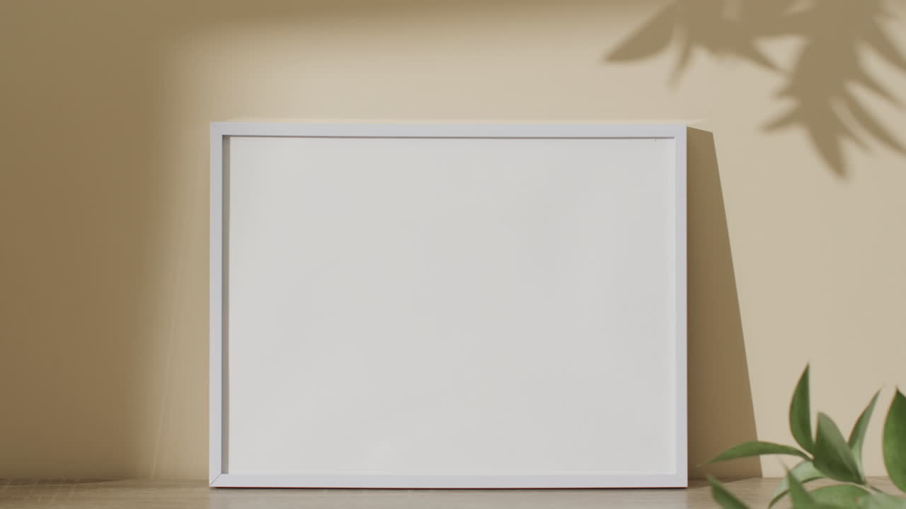 marco negro con espacio de copia en fondo blanco y sombra de hoja contra la pared amarilla