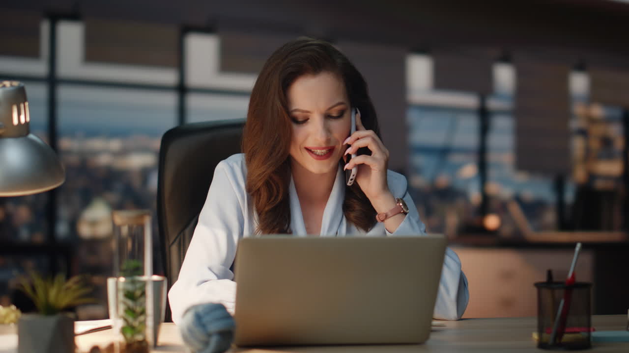 Donna che fa una chiamata di lavoro e prende appunti in ufficio. Capo donna sorridente che parla