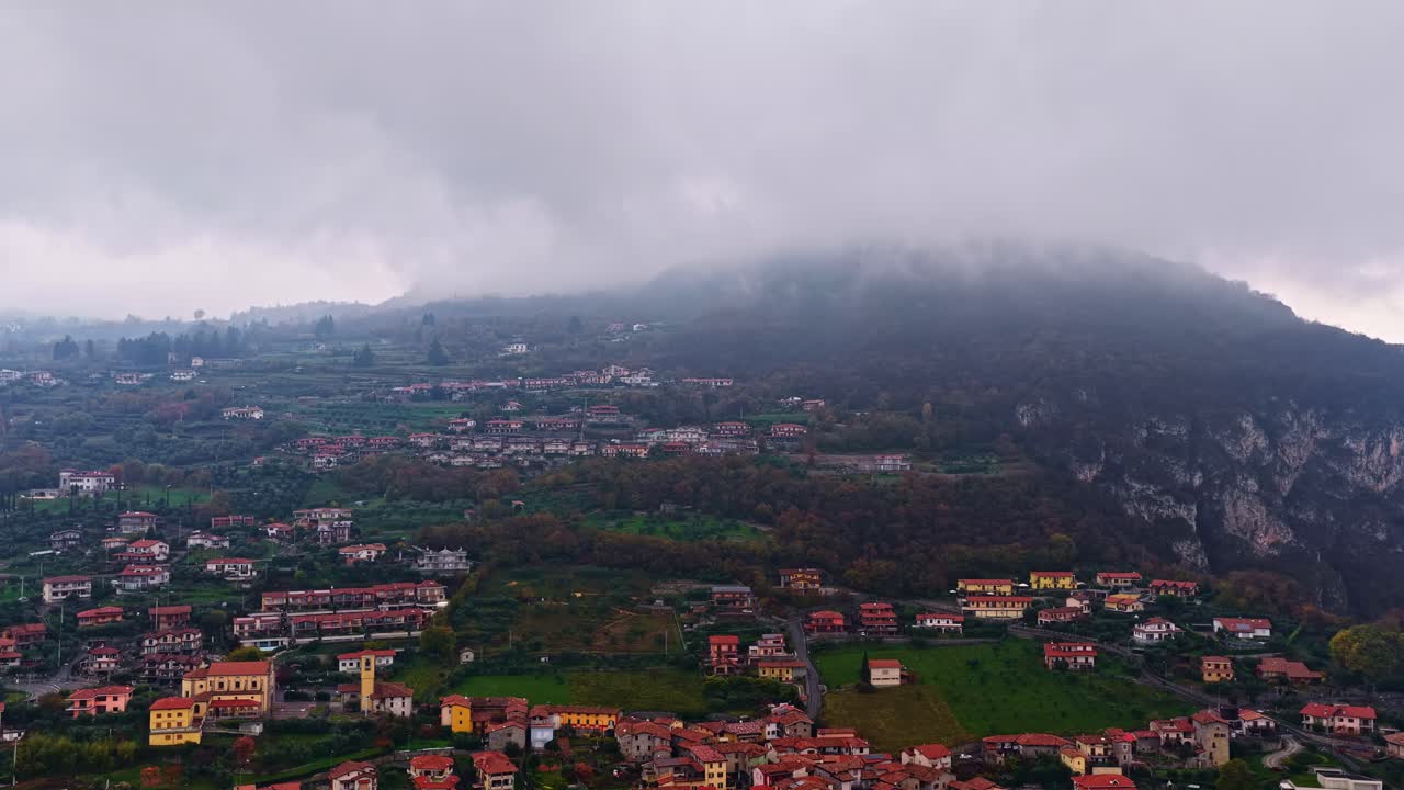Vista aerea in timelapse del Lago d'Iseo con nuvole basse che si muovono accanto alla montagna, alle città collinari e al paesaggio avvolto dalla nebbia