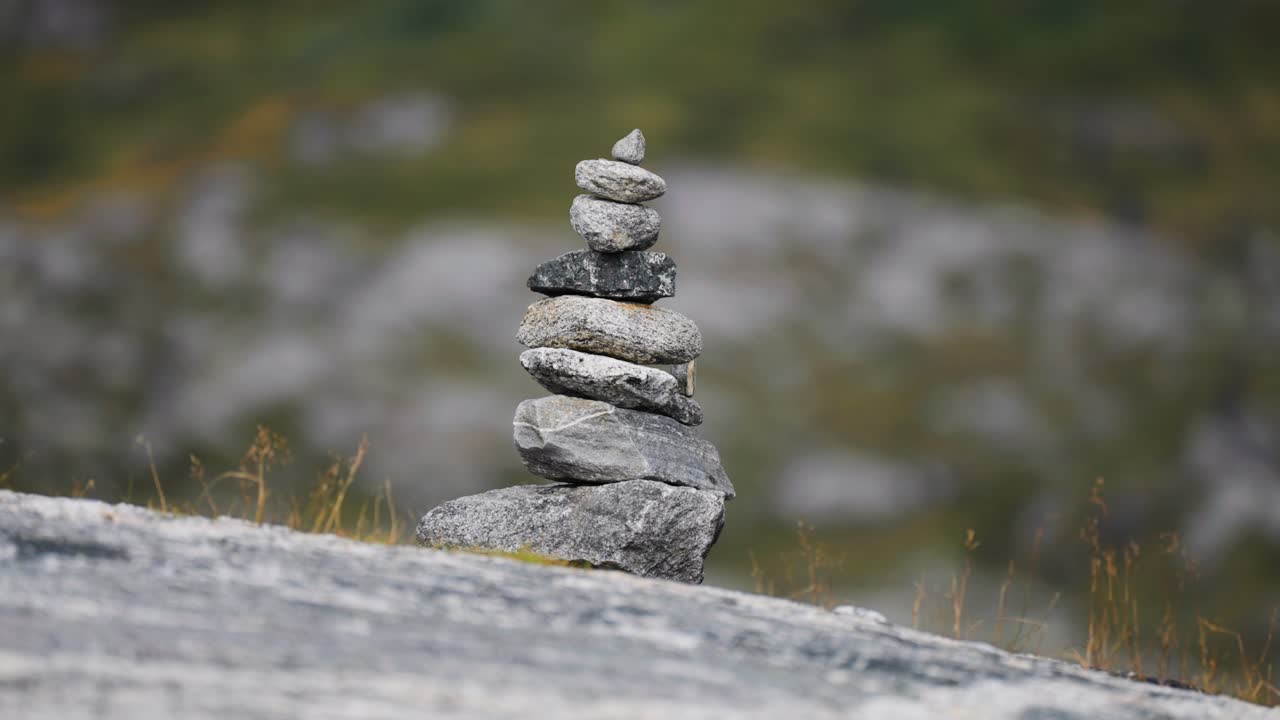 A stack of stones, intricately balanced on top of each other, with a blurred natural background.