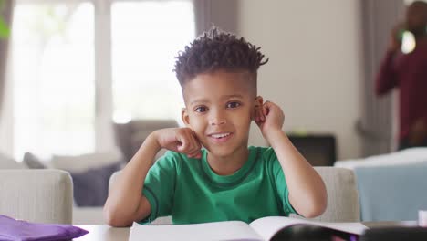 Glücklicher-Afroamerikanischer-Junge,-Der-Am-Tisch-Sitzt-Und-Online-Unterricht-Hat
