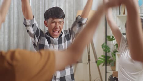 close up of asian teen group sitting and discussing at home. take each others hands, support each other, holding and raising hands motivation screaming