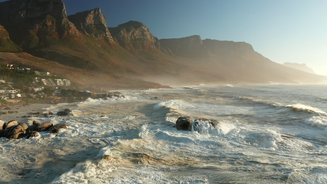 olas del océano rompiendo en la costa rocosa de la playa de bakoven al amanecer en ciudad del cabo, sudáfrica
